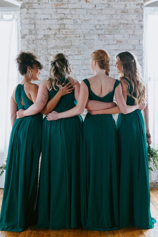 Group of bridesmaids wear Kennedy Blue bridesmaid dresses in emerald