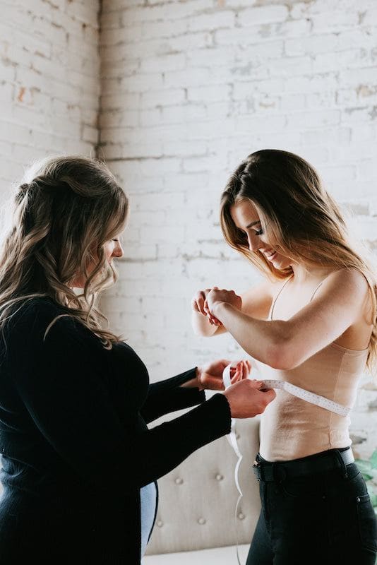 Two women take measurements to find their bridesmaid dress size